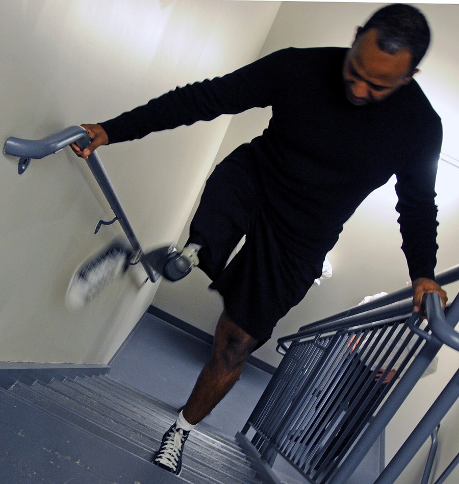 A man with a lower-limb prosthesis climbing stairs using the handrail